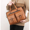 A person holds a tan brown PU leather business briefcase bag against a light colored shirt.