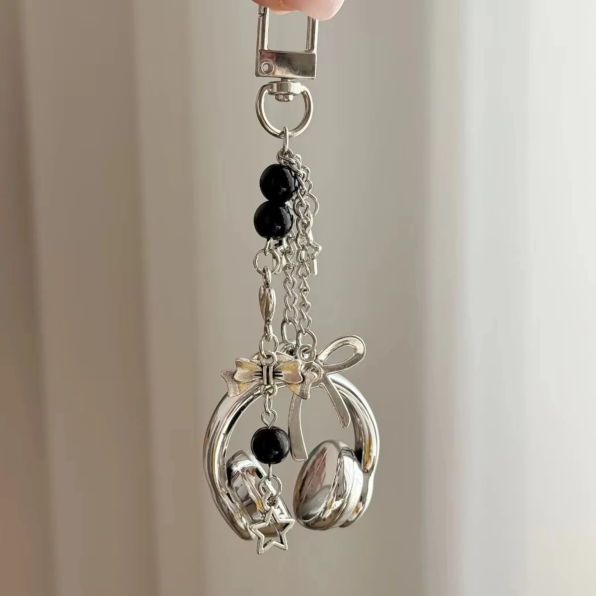 Silver music headphone keychain with black beads and a bow charm