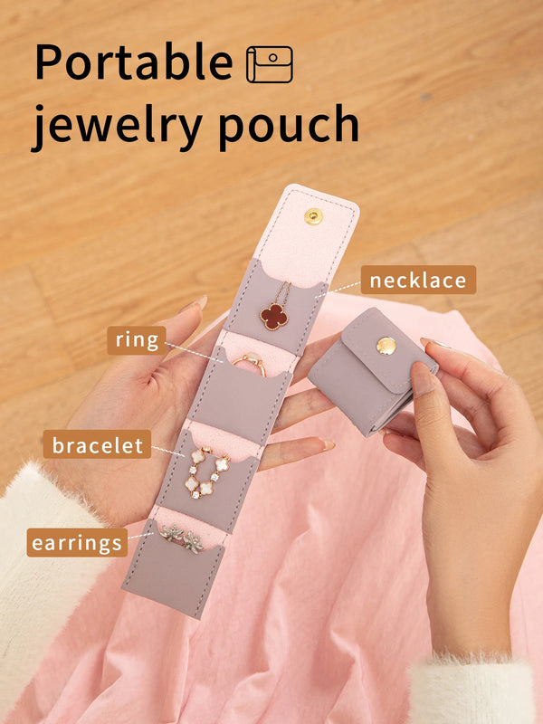 A hand holds a long, layered, pastel purple jewelry pouch displaying various pieces like rings, bracelets, and earrings.