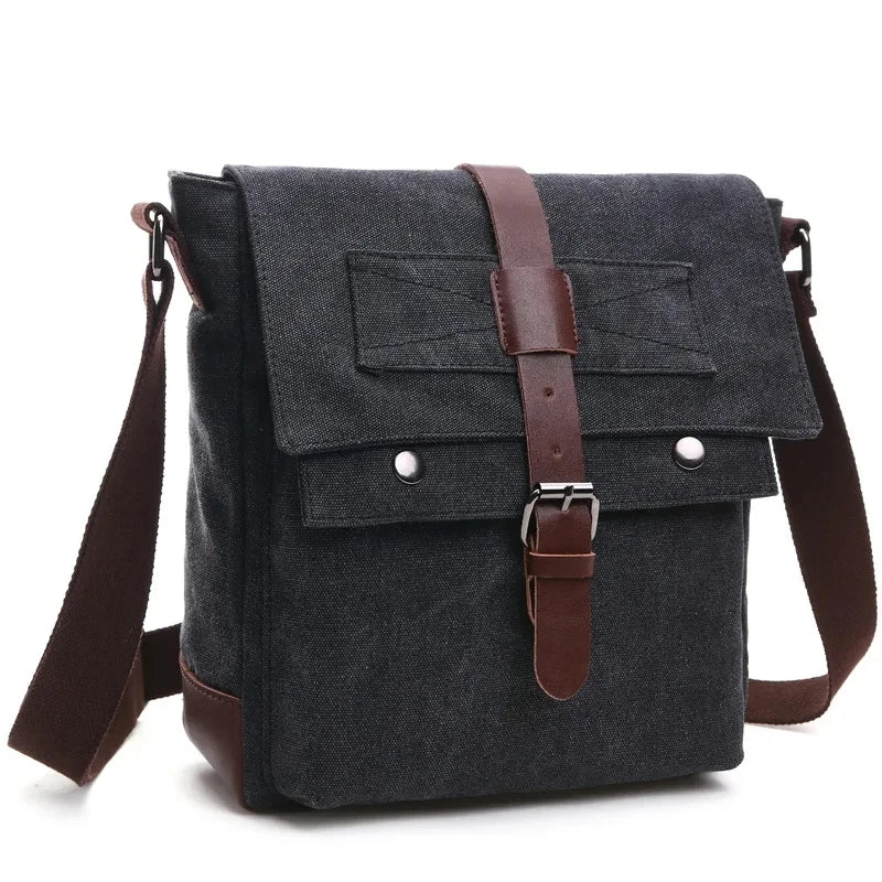 A dark gray canvas messenger bag with brown leather accents and straps.