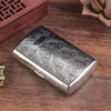 Silberne Vintage-Gravierte Metallsigarette-Etui auf dunklem Holz.