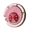 Ganchillo de mesa plegable de aluminio con forma de mariposa rosa y oro rosa.