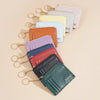 A collection of various colored ultra-thin card holder wallets with keychain attachments arranged diagonally.