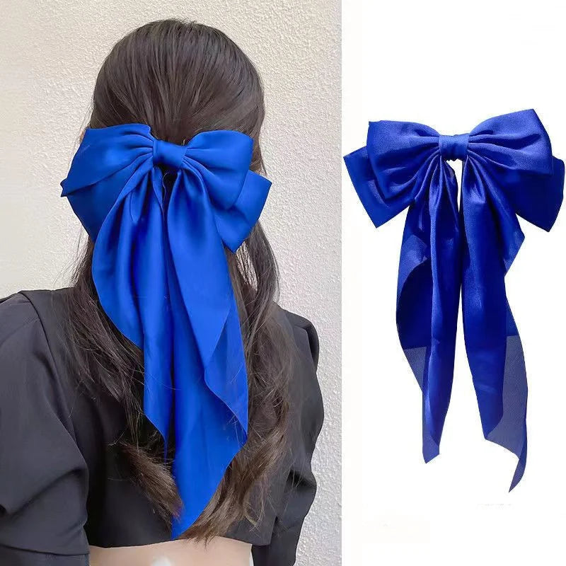 A royal blue silk bow accessory shown as a fabric tie and hair clip for a ponytail.