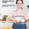 A woman holds an insulated portable lunch bag on a wooden table, demonstrating its use for healthy food.