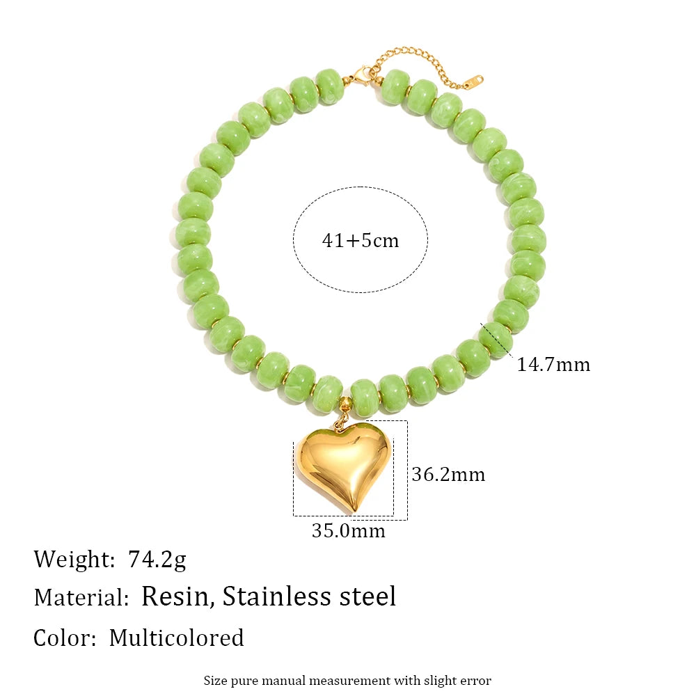 A gold-toned bead necklace featuring light green resin beads and a heart-shaped gold charm.