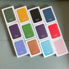 A collection of colorful leather wallet cases in various shades including green, yellow, black, blue, red, purple, and pink.