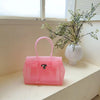 Pinkes Sommer-Gelidertasche auf weißem Regal neben einer Topfpflanze