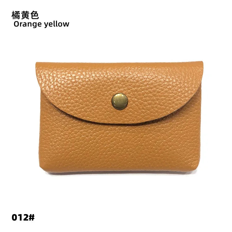 A tan genuine leather card holder or coin purse with a gold-toned metal clasp.