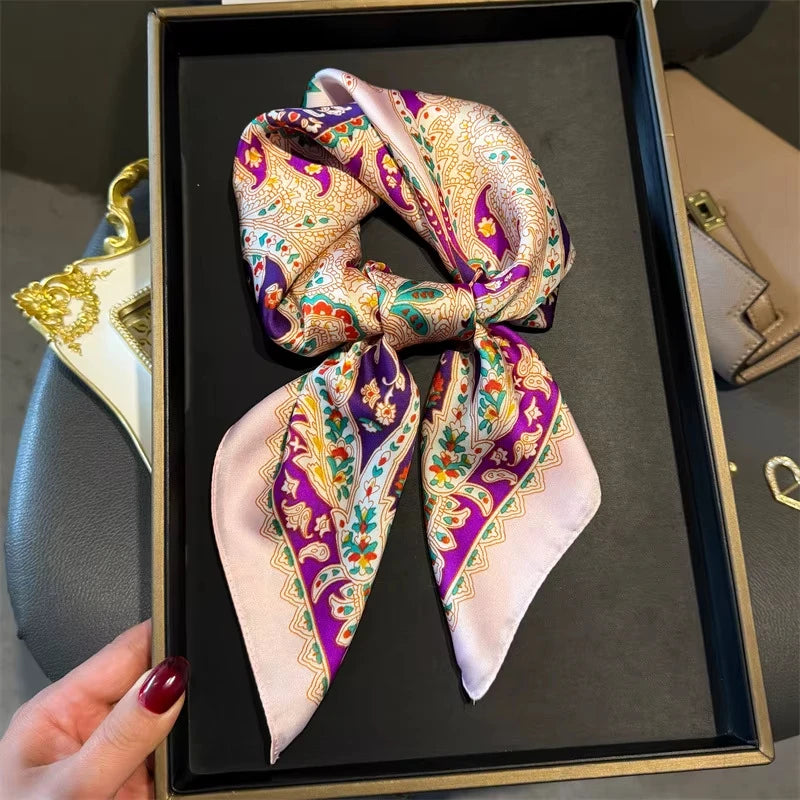 A silk paisley scarf tied in a bow is displayed in a black frame.