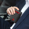 A hand is holding a black carbon fiber wallet with an ID window inside a dark blue suit jacket.