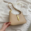 A beige PU leather hobo shoulder bag with gold hardware is held against a white background.