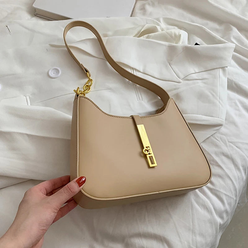 A beige PU leather hobo shoulder bag with gold hardware is held against a white background.