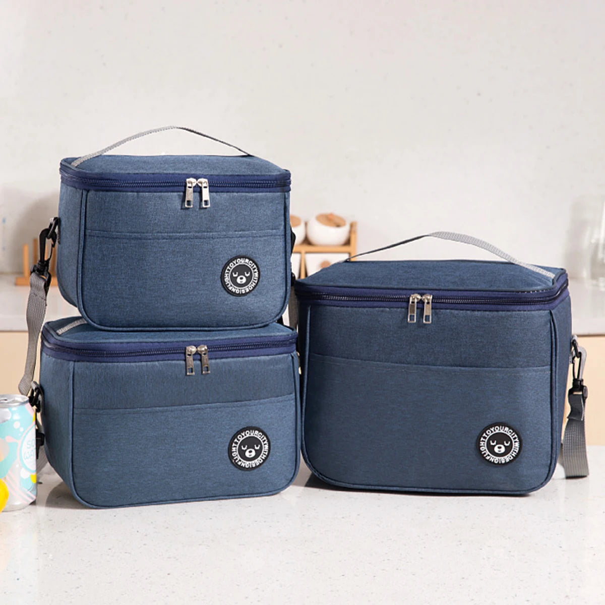 Two navy blue insulated lunch tote bags with adjustable straps resting on a white surface.