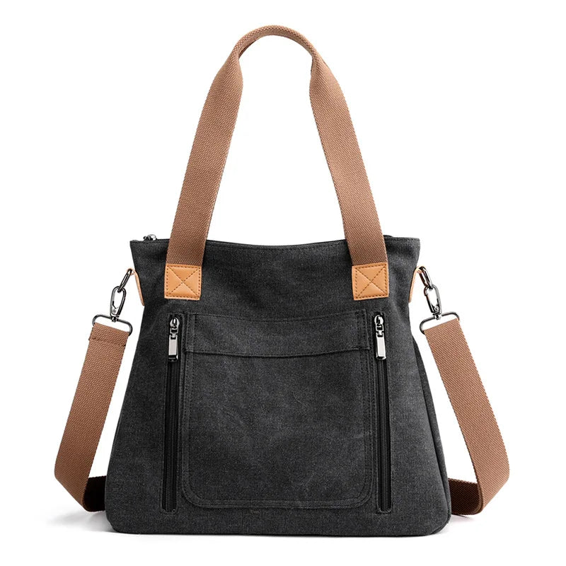 A dark gray canvas tote bag with tan leather straps and zipper details.