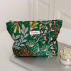 A vibrant green cosmetic pouch with floral embroidery and a white tag labeled YETONADO resting on a gray surface.