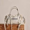 A beige vintage PU leather crossbody tote bag with a light strap resting on a wooden surface.