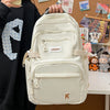 A cream-colored lightweight nylon college backpack being held by a person against a brown background.