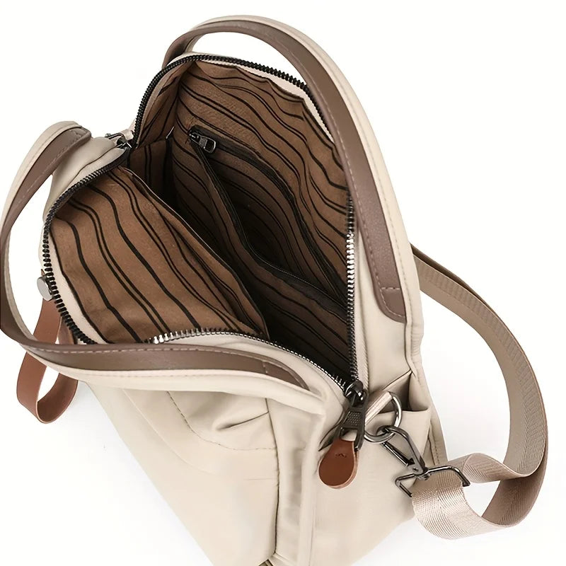 A beige shoulder crossbody bag with a zippered interior pocket and tan leather strap.