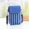 A navy blue denim mini messenger bag with striped fabric and a blue flap is shown on a white surface.