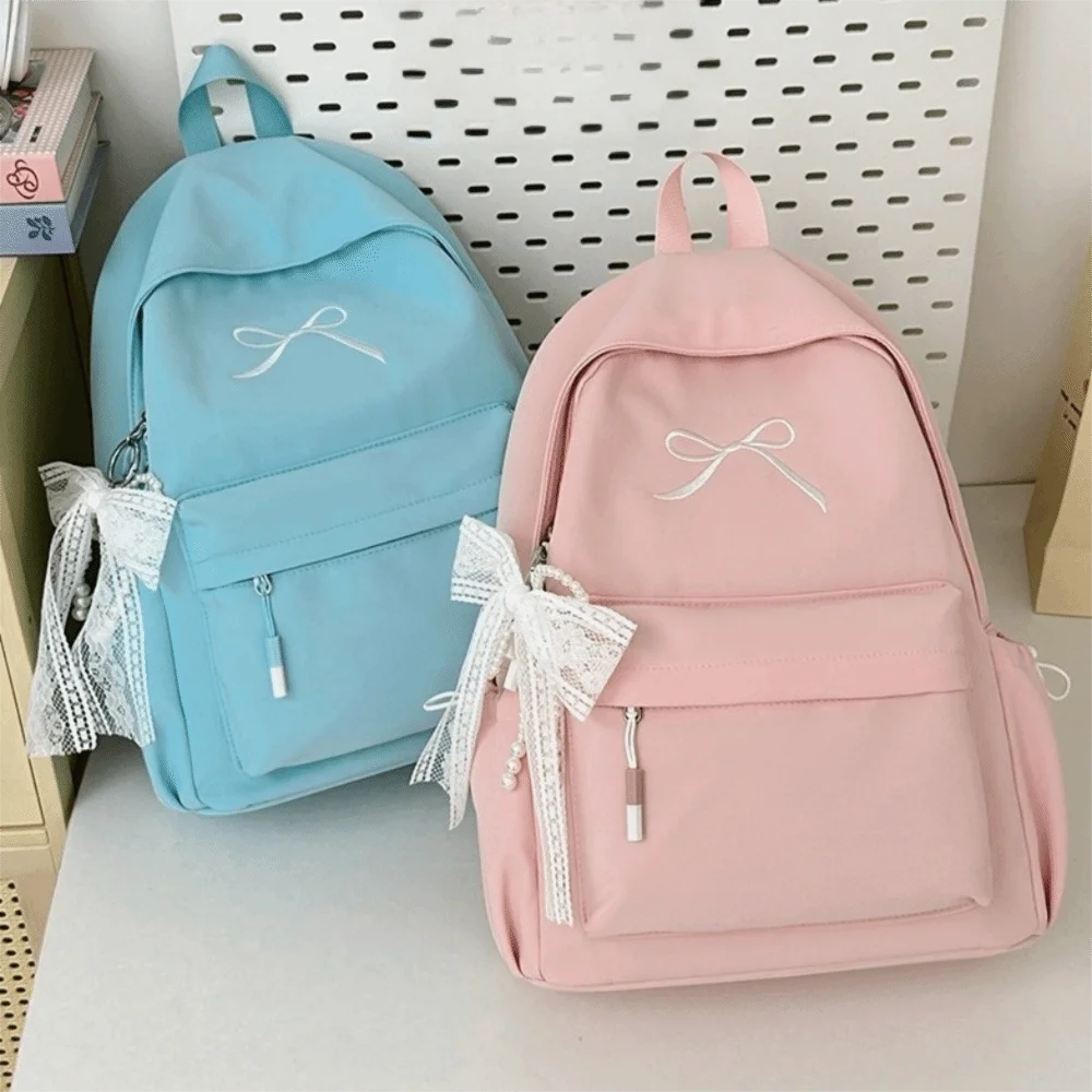 A pink embroidered backpack and a light blue embroidered backpack are displayed on a white surface.