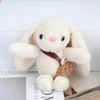A fluffy white plush rabbit with brown accents, used as a keychain.