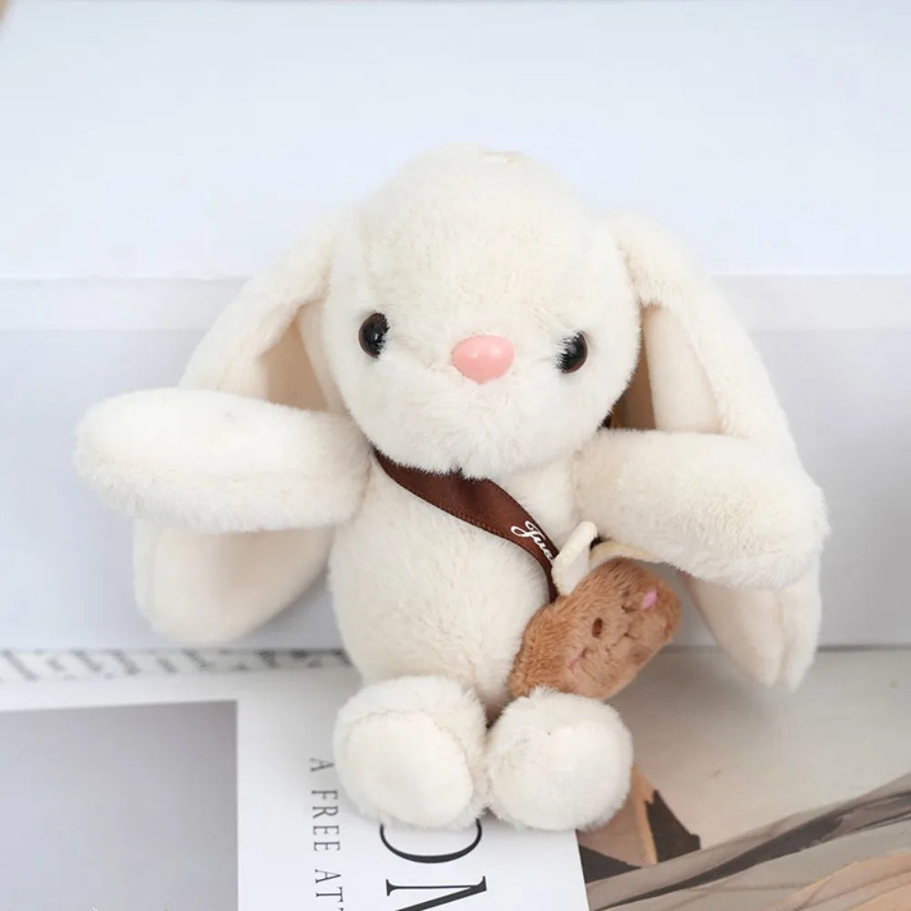 A fluffy white plush rabbit with brown accents, used as a keychain.