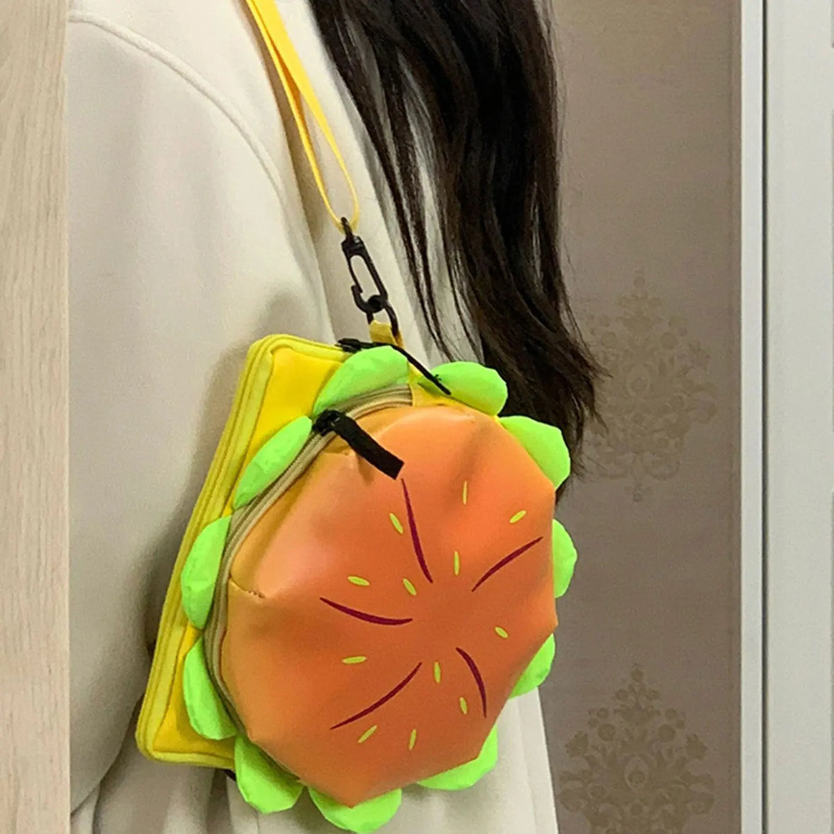 An orange cheeseburger novelty backpack with green accents hangs from a yellow strap.