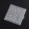 A rectangular silver decorative metal cigarette storage box with intricate scrollwork design.