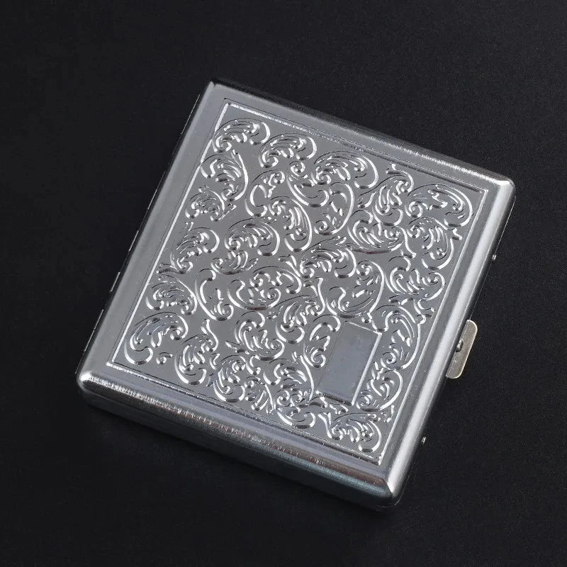 A rectangular silver decorative metal cigarette storage box with intricate scrollwork design.