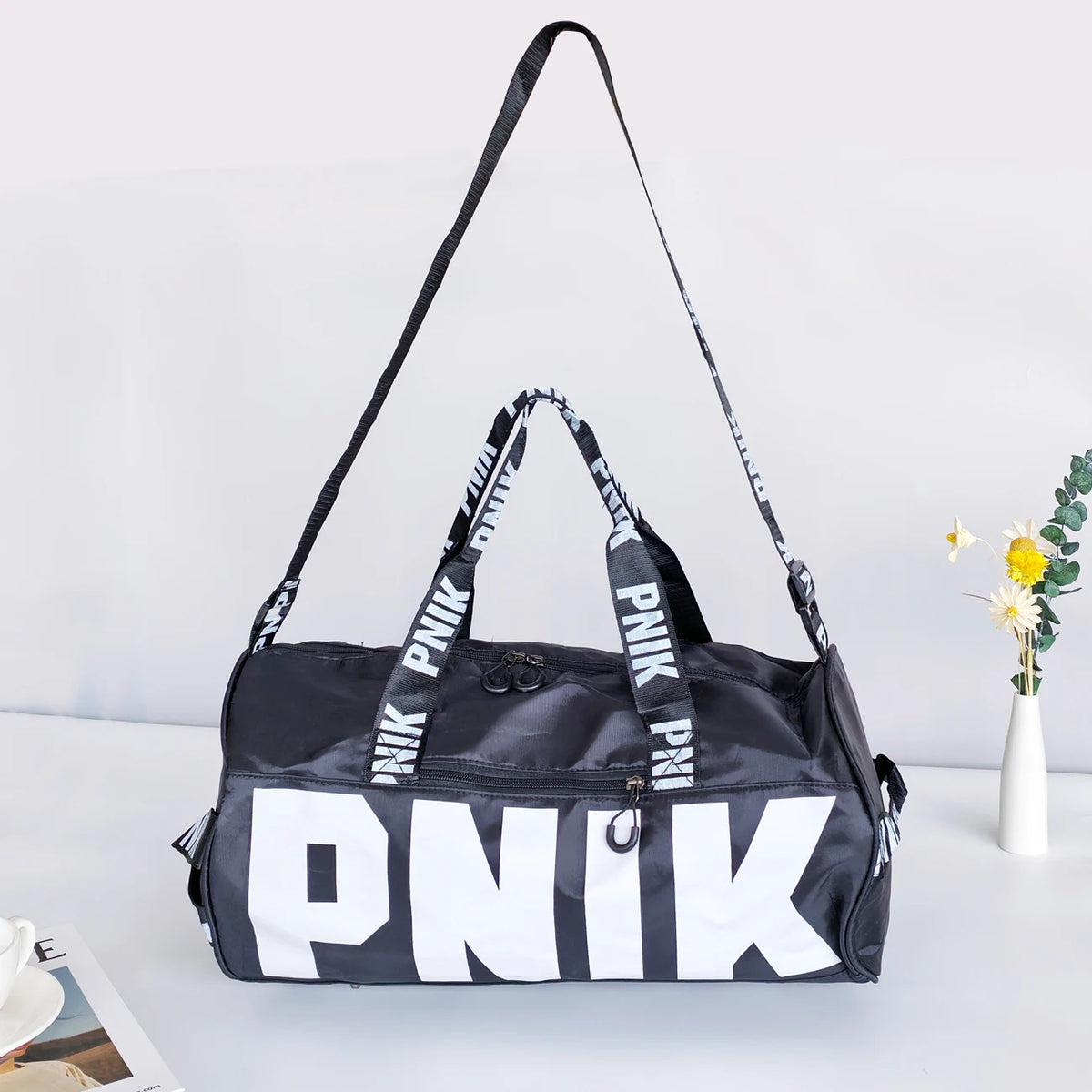 A black and white Nike shoulder bag with black straps, featuring the brand name PNIK printed on the front.