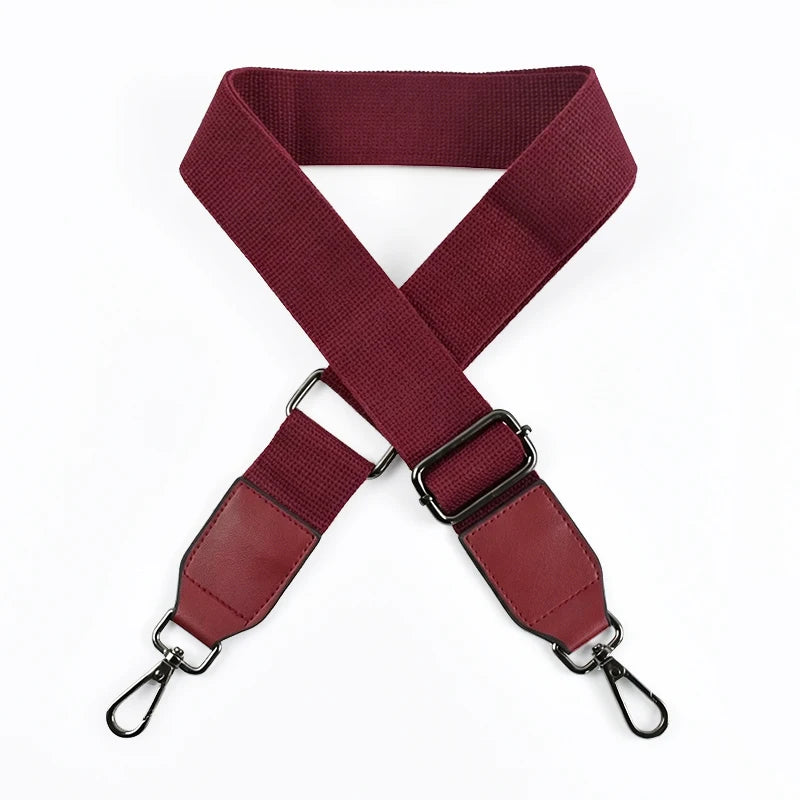 A maroon canvas cotton bag strap with black metal hooks, shown in an X-shape.