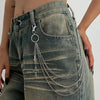 A close-up of a distressed denim skirt featuring a silver chain belt with pearl accents and dangling charms.