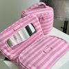 A pink and white striped Y2K makeup bag with a clear mirror and zipper is displayed on a white surface.