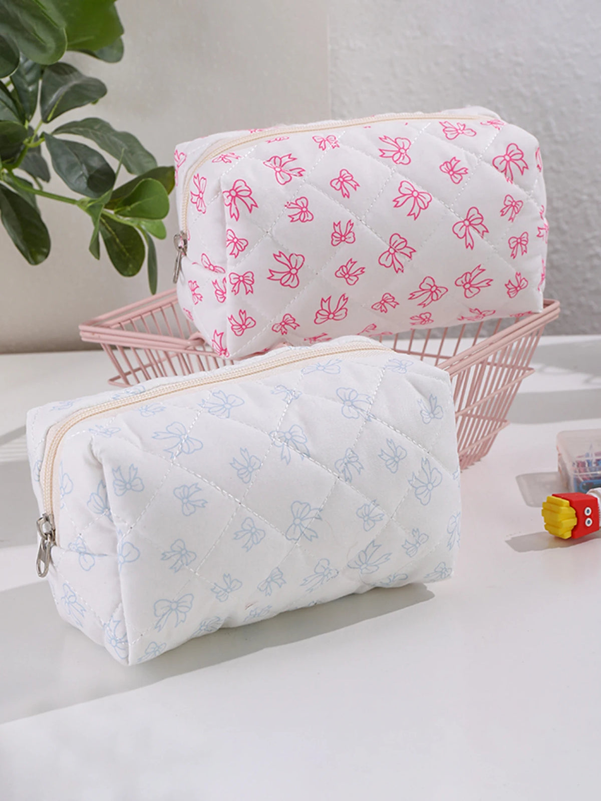 Dos neceseres acolchados blancos para maquillaje con estampados de lazo rosa y azul