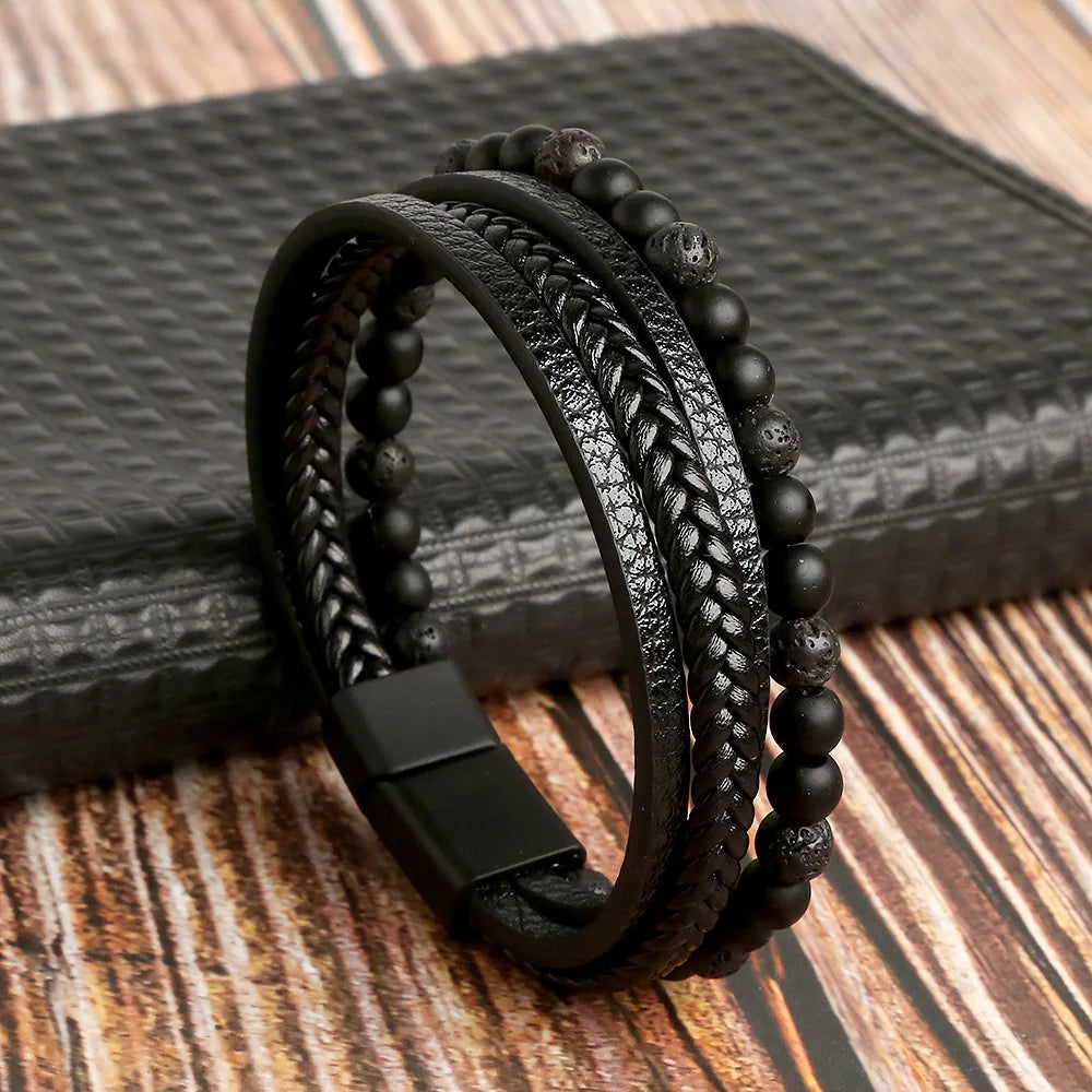 A stack of black leather bracelets featuring various textures and tiger eye beads resting on a dark surface.