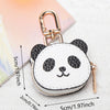 Cartera de moneda de panda blanco y negro con llavero dorado sobre fondo claro.