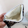 A leopard print cosmetic bag is shown open, displaying a light beige lining and dark brown and black patterned exterior.