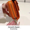 An orange zippered card holder with a gold zipper pull is being held by a hand.