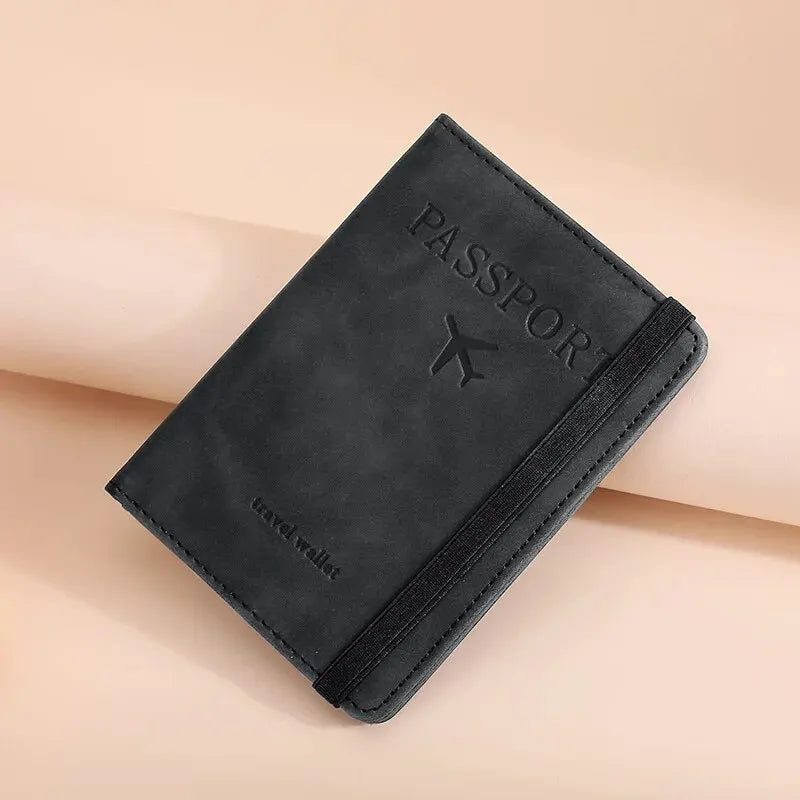 A black leather passport holder with a flap and stitching is shown diagonally on a light pink background.