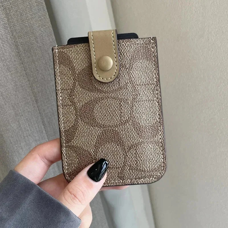 A hand holds a brown patterned PU leather card holder purse with a leather flap and stud.