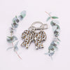 A leopard print bow and heart bag charm keychain attached to a leafy green branch.