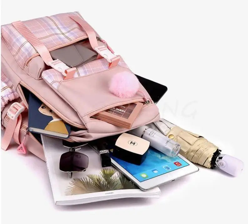 A pink canvas backpack with a plaid pattern and a fluffy pink pom-pom, next to a smartphone.