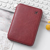 A deep burgundy leather passport and document holder resting on a white desk next to a keyboard.