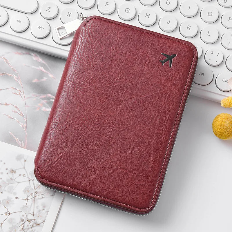 A deep burgundy leather passport and document holder resting on a white desk next to a keyboard.