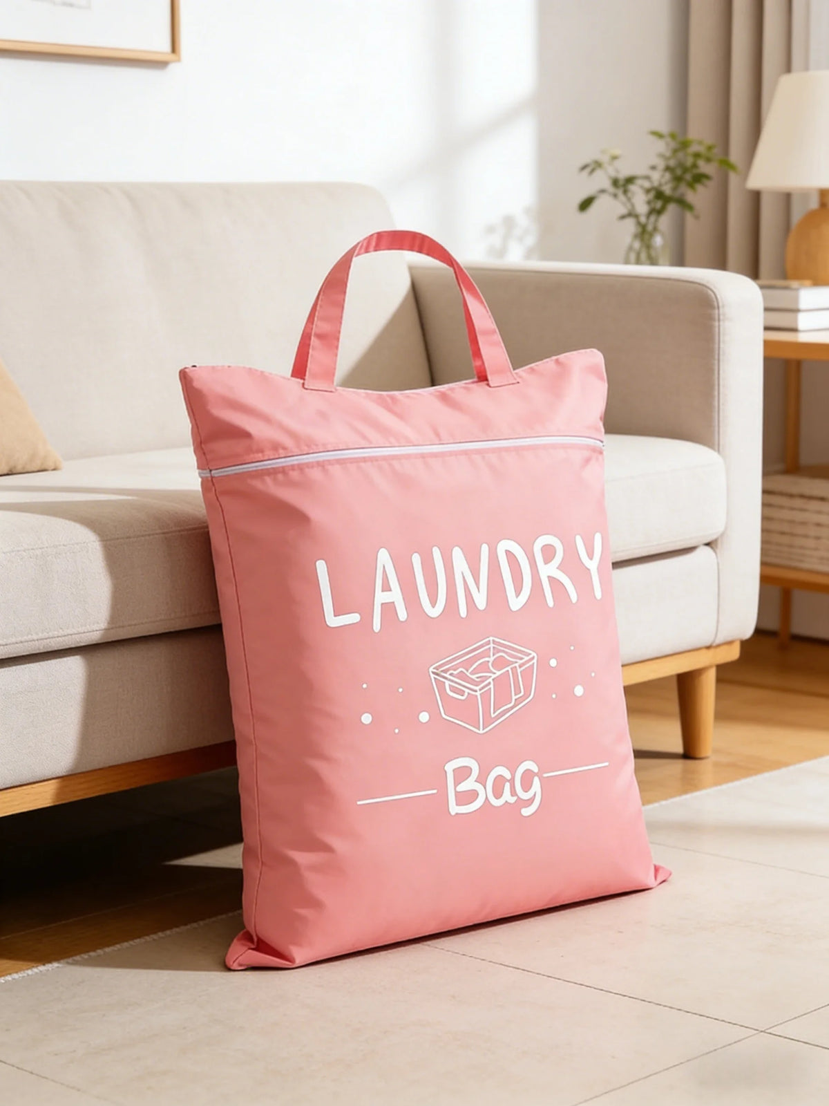 A pink laundry bag with a handle is placed on a light-colored floor in a bright living room setting.
