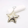 A shiny gold star-shaped leather key chain pendant hanging from a silver keyring.