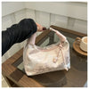 A light pink embroidered crossbody shoulder bag resting on a wooden surface.