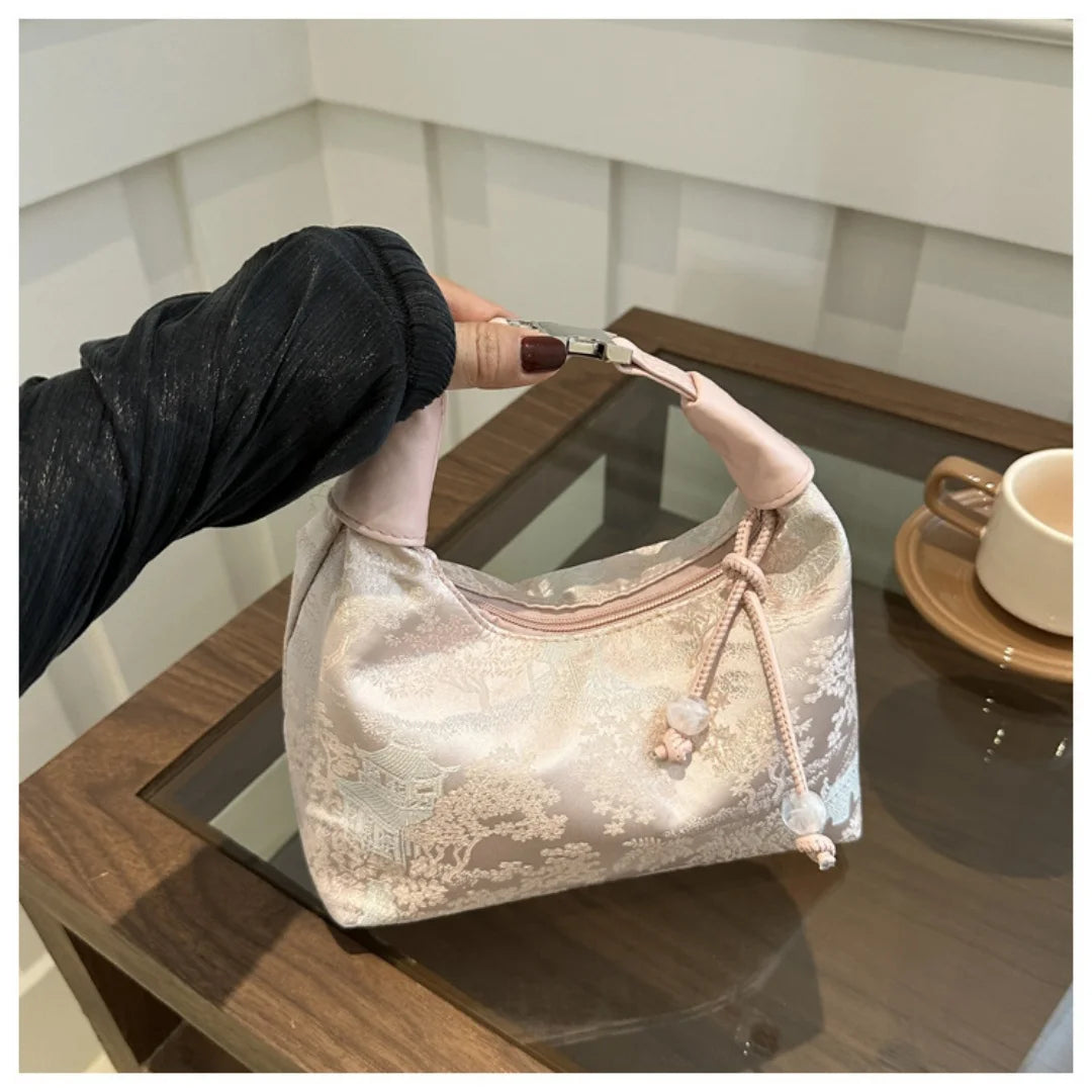 A light pink embroidered crossbody shoulder bag resting on a wooden surface.