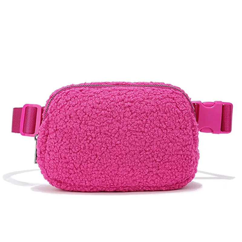 A pink fleece crossbody belt bag with a zipper and pink strap.